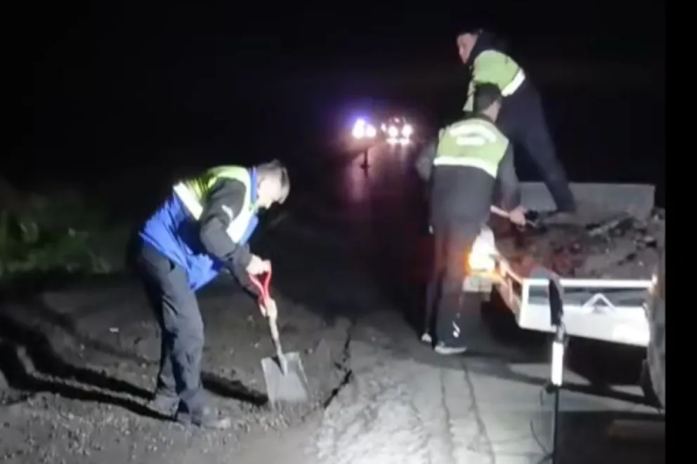 El director de Defensa Civil, Roque Bazán, tapa junto a dos agentes municipales un bache profundo en la Ruta Provincial 65.